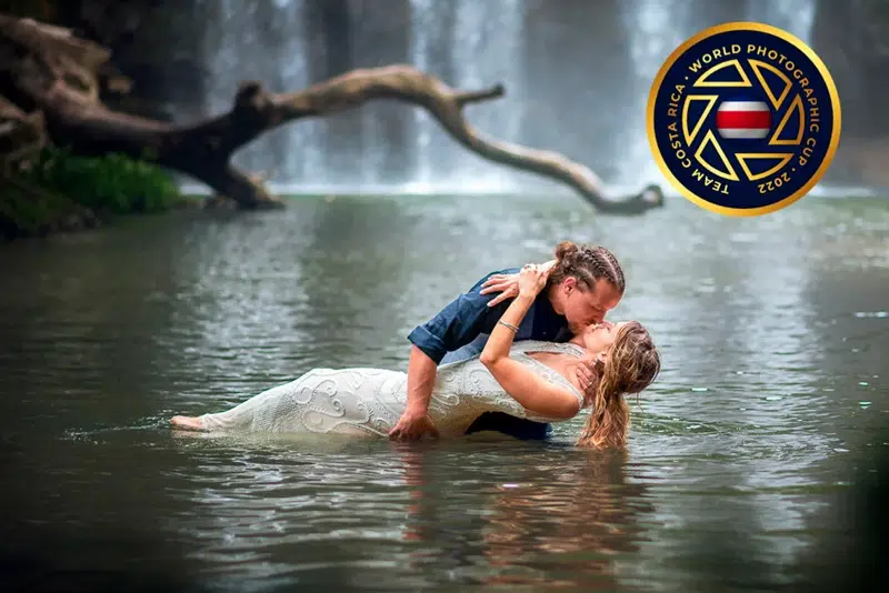 Held in love beneath the falls Groom holding bride in his arms in the water at the base of a waterfall in Costa Rica