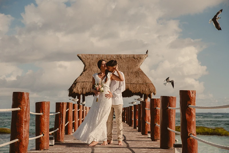Eternal Love by the Sea Bride and groom hugging on a pier with seagulls flying around and the ocean in the background.