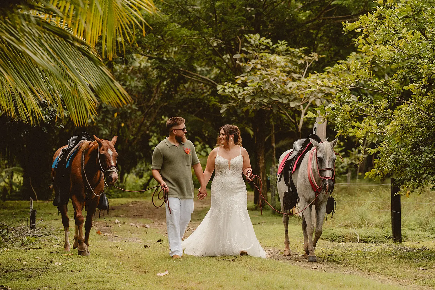 Bride and groom walking outdoors beside horses on a tropical path. Monteverde, La Fortuna, Manuel Antonio, Tamarindo, Puerto Viejo Costa Rica. Uvita
