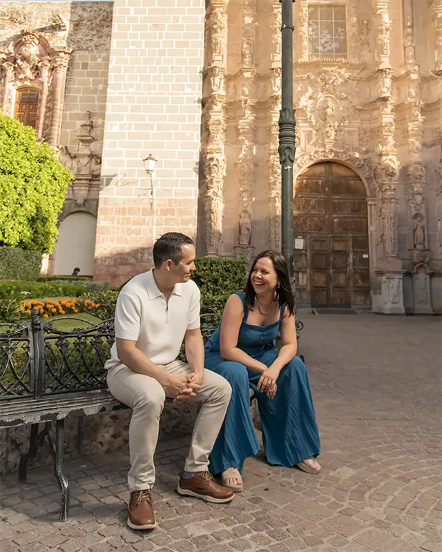 Joice Dahianna, La Fortuna wedding photographer, sitting with her partner Diego in front of a colonial church, Costa Rica
