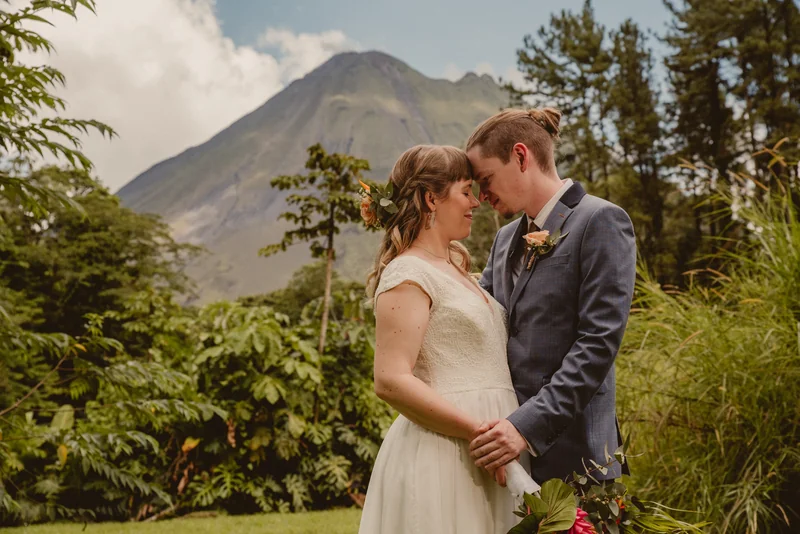 La Fortuna wedding photographer capturing the bride and groom's ceremony portrait with Arenal Volcano rising behind them, Costa Rica