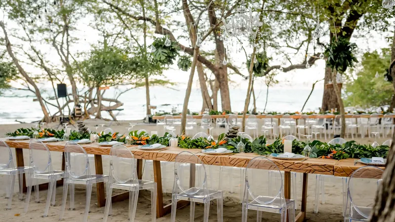 Long wooden banquet table with greenery for a beachfront wedding dinner at Casa de Playa, Andaz Costa Rica