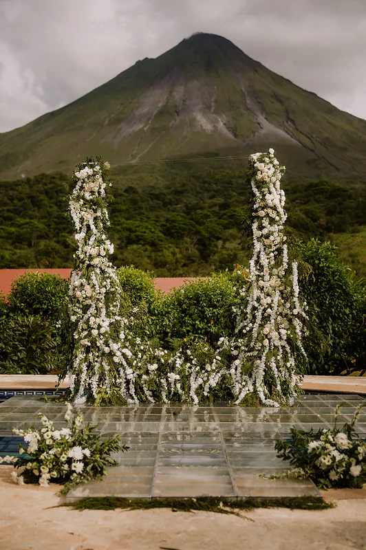 White floral ceremony columns and glass aisle with Arenal Volcano in the background at Arenal Kioro, La Fortuna, Costa Rica