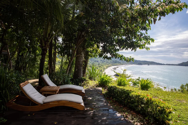 Lounge chairs on a garden terrace overlooking Playa Espadilla at Arenas del Mar Resort, Manuel Antonio, Costa Rica