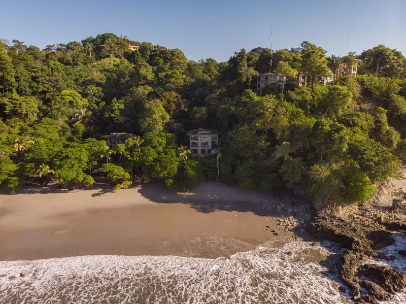 Aerial view of the beach cove and rainforest-covered hillside at Arenas del Mar Resort, Manuel Antonio, Costa Rica