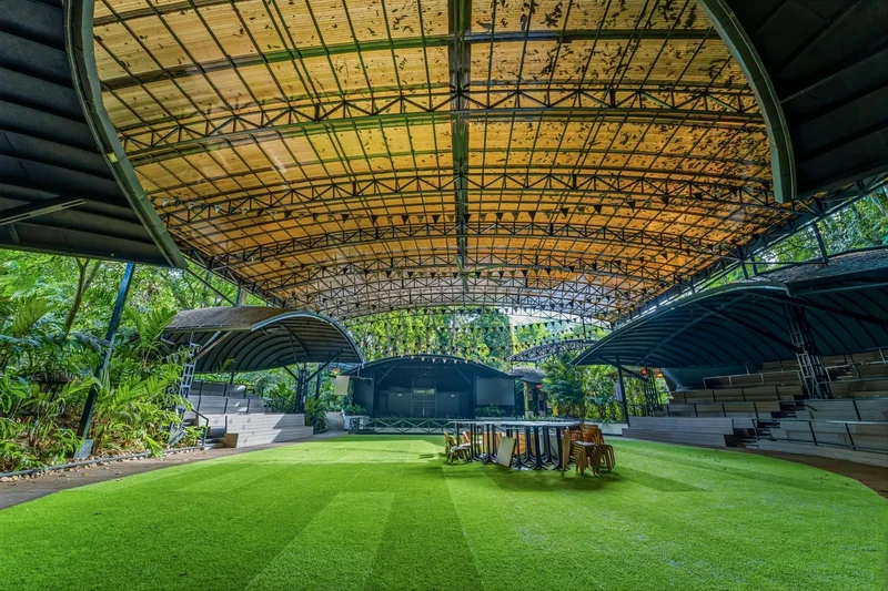 Large covered open-air event pavilion with a grass floor surrounded by rainforest at Casa del Río, La Fortuna, Costa Rica