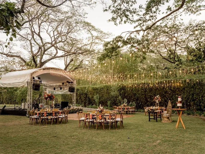 Garden Plaza wedding reception with stage, string lights and wooden tables at El Mangroove, Playa Panamá
