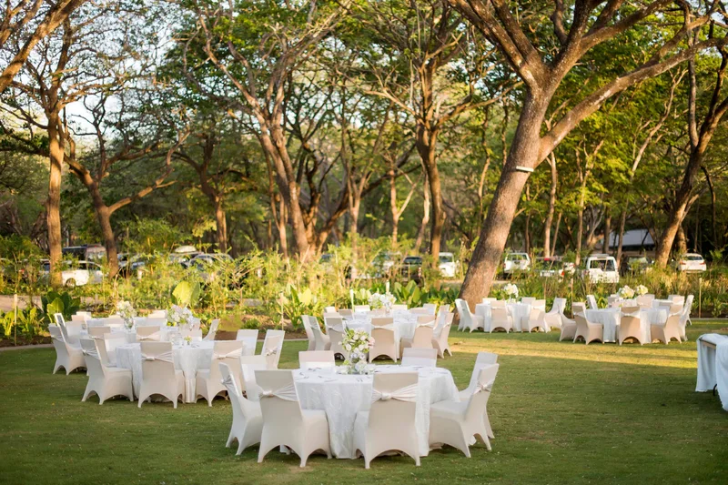 Round tables with white linens for an outdoor wedding reception in El Mangroove's tropical garden