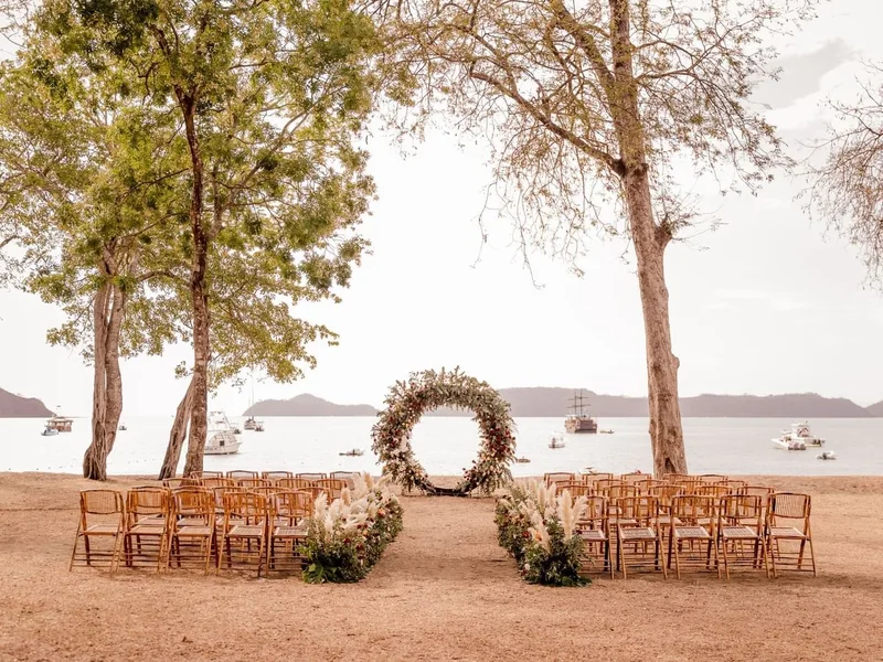 Beach wedding ceremony with a circular floral arch facing the Gulf of Papagayo at El Mangroove, Costa Rica