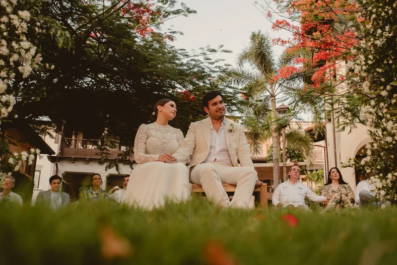 Bride and groom seated during their garden wedding ceremony in Las Catalinas, Guanacaste, surrounded by tropical trees