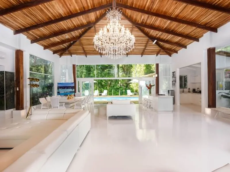 White open-plan great room with a crystal chandelier and wood beam ceiling at Le Caméléon Hotel, Caribbean coast of Costa Rica