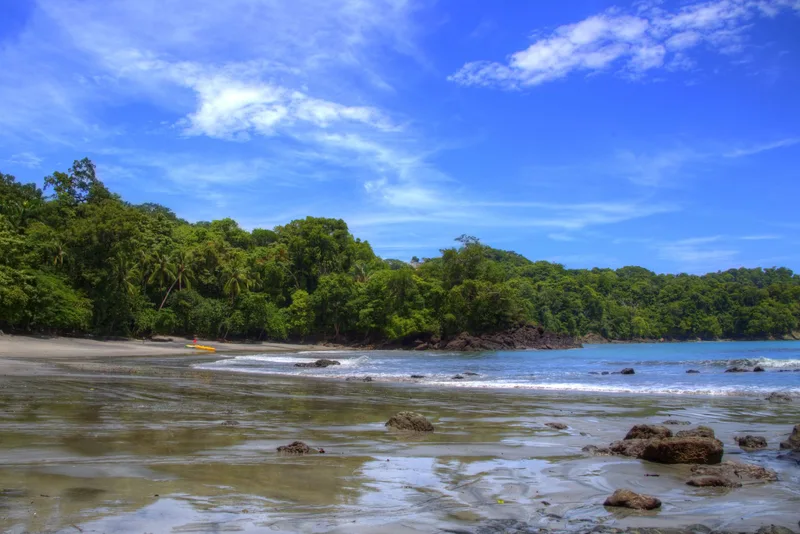 Private rainforest-lined beach with calm water and rocks at Tulemar Resort wedding venue in Manuel Antonio, Costa Rica