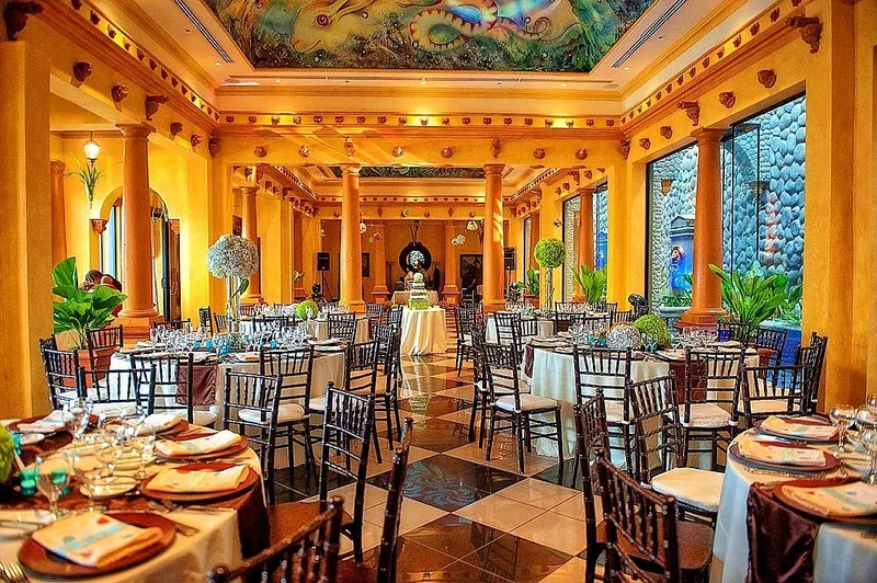 Wedding reception set with round tables and a painted ceiling in the ornate indoor hall at Villa Caletas Hotel, Jacó, Costa Rica