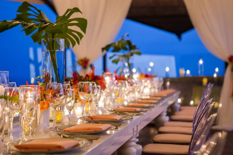 Long wedding reception table with orange flowers, candles and draped curtains at blue hour at Villa Punto de Vista, Manuel Antonio