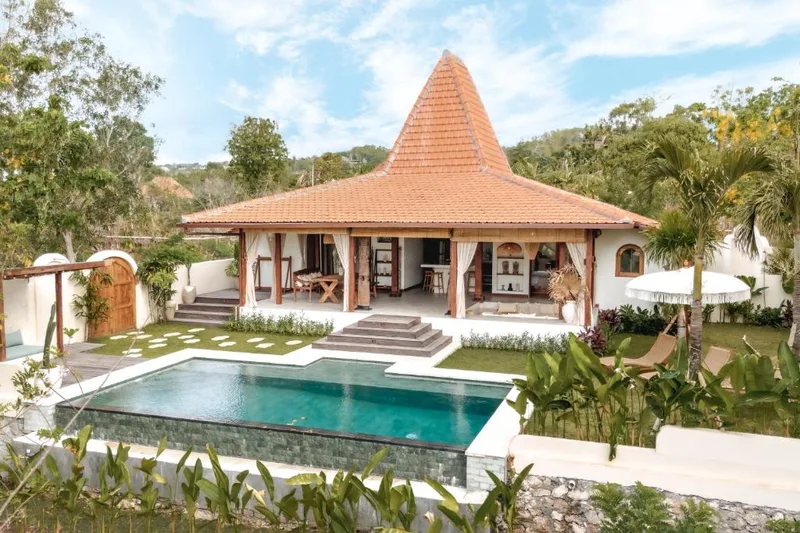 Balinese-style villa with a pagoda roof, lawn and turquoise pool at Villa Wanderlust wedding venue in Jacó, Costa Rica