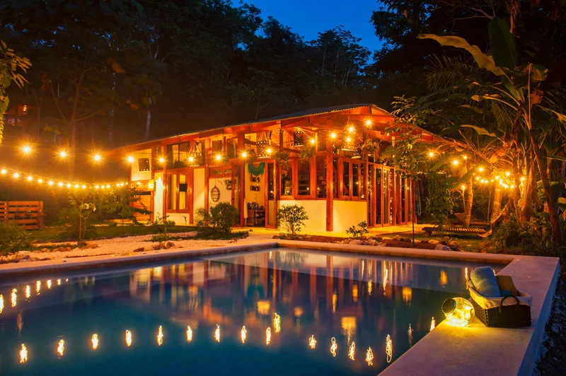 Pool glowing under string lights at night in front of the main house at Villa Wanderlust, a private wedding venue in Jacó, Costa Rica