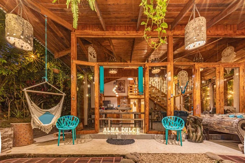 Open-air wooden jungle lounge with a hammock, hanging lanterns and turquoise chairs at Villa Wanderlust wedding venue in Jacó, Costa Rica
